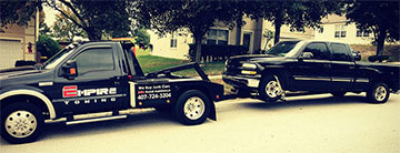 Orlando Towing Service truck towing a black pickup truck - Empire Towing, LLC