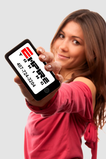 Woman holding a phone showing the Empire Towing logo and phone number